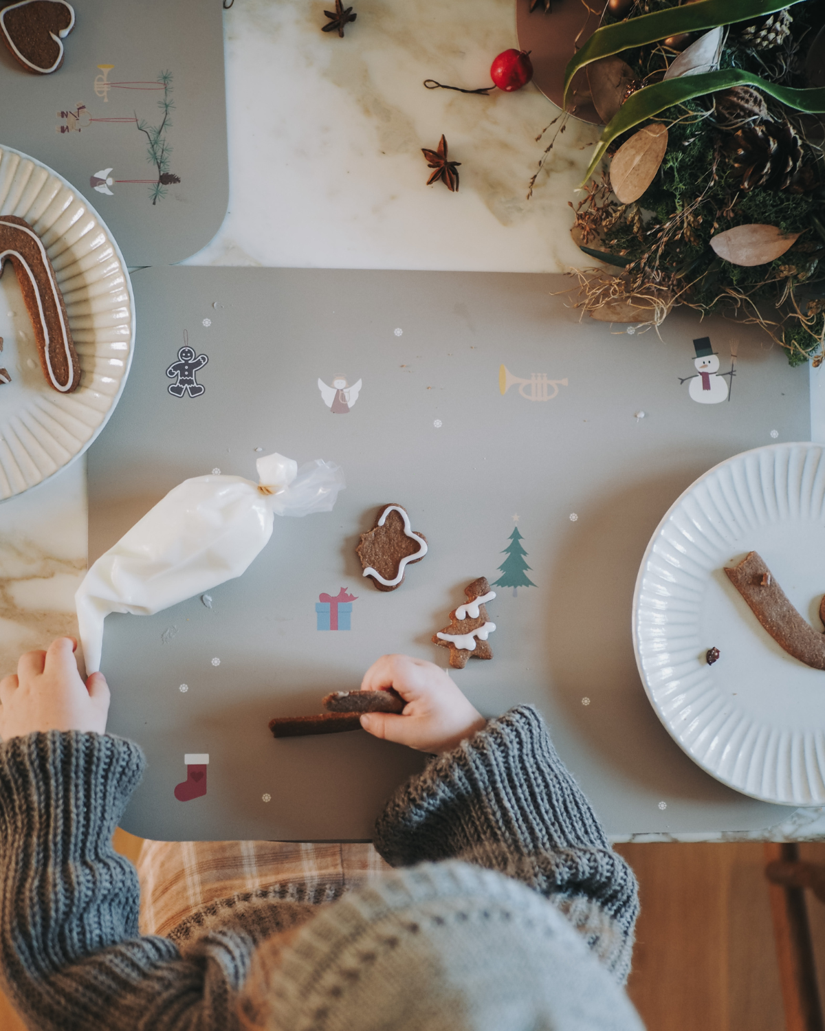A placemat with a winter-themed design featuring snowflakes, Santa Claus, and Christmas-related icons on a olive haze gray background.
