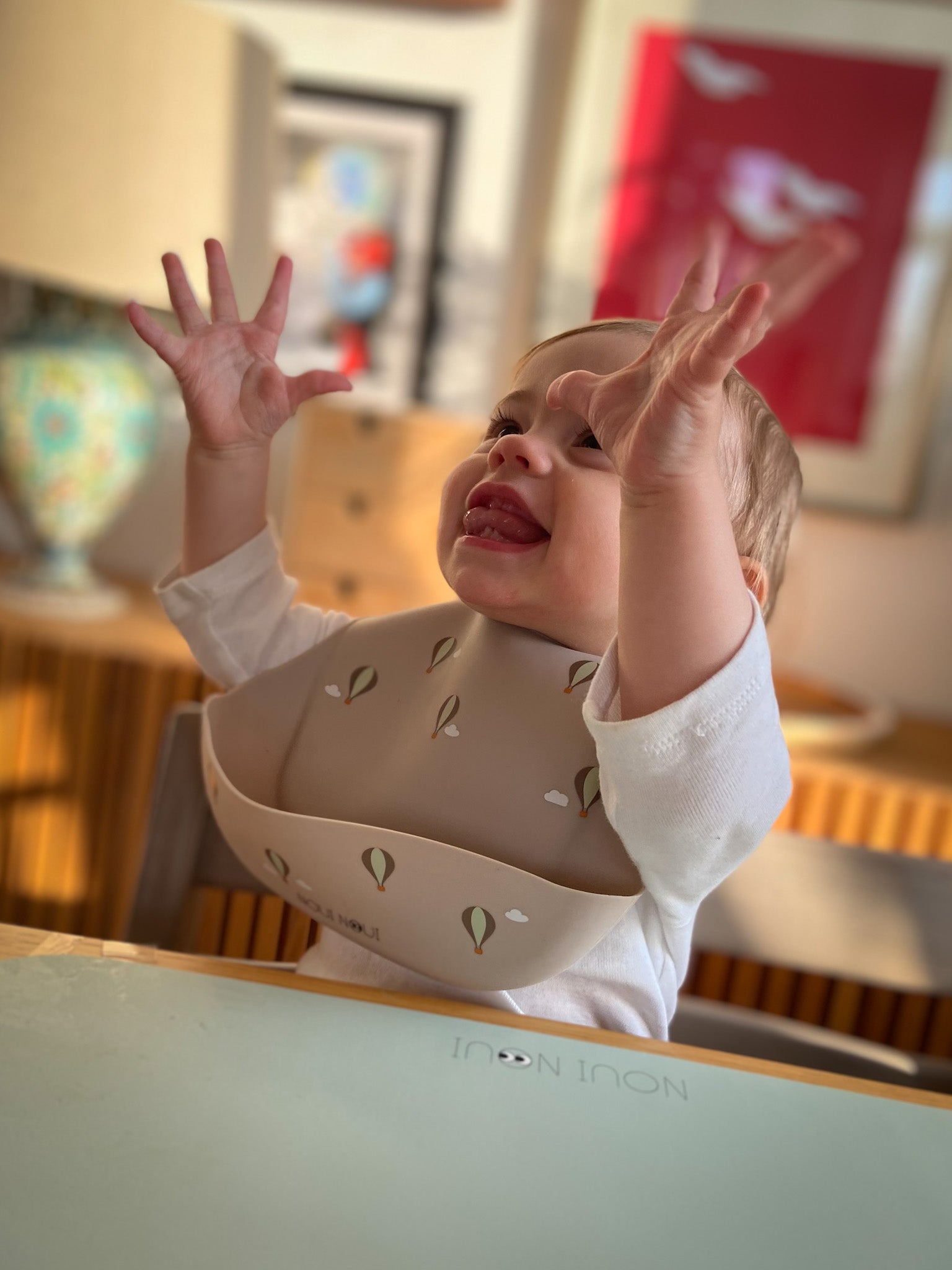 A child wearing our nude silicone bib with small cute hot air balloon pattern and an adjustable neck strap.