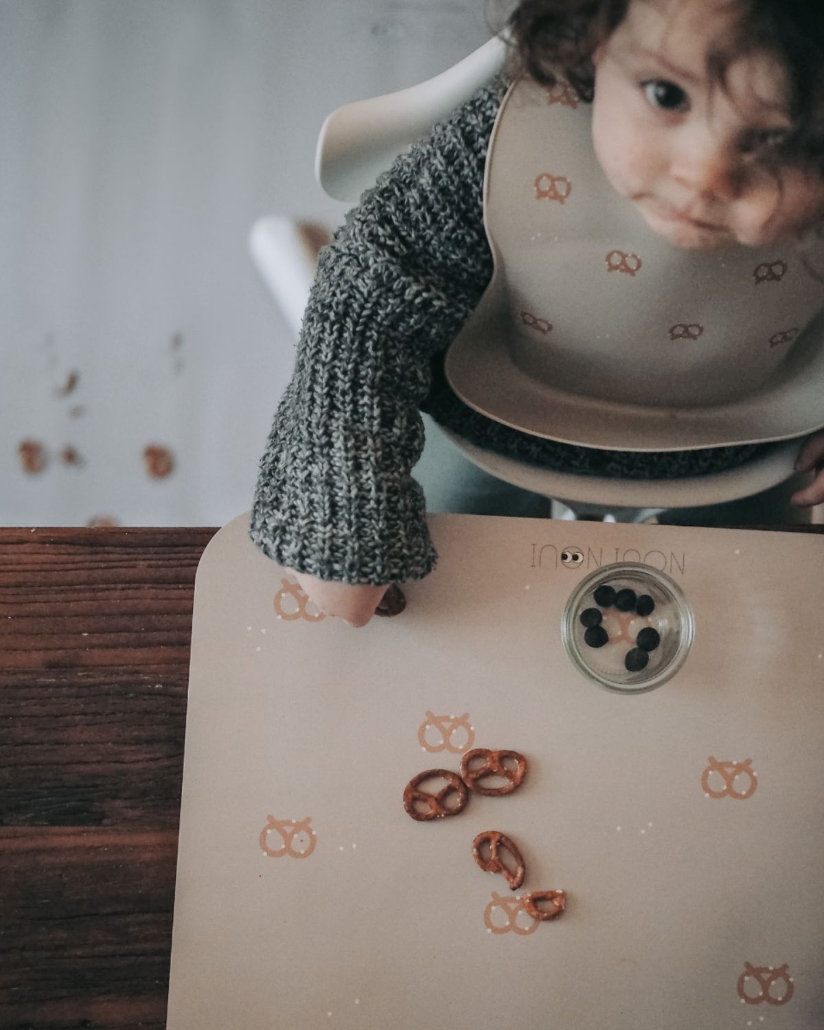 A rectangular grey powder high chair floor mat. Size 120 x 95 cm. Paired with our placemat with cute brezn.