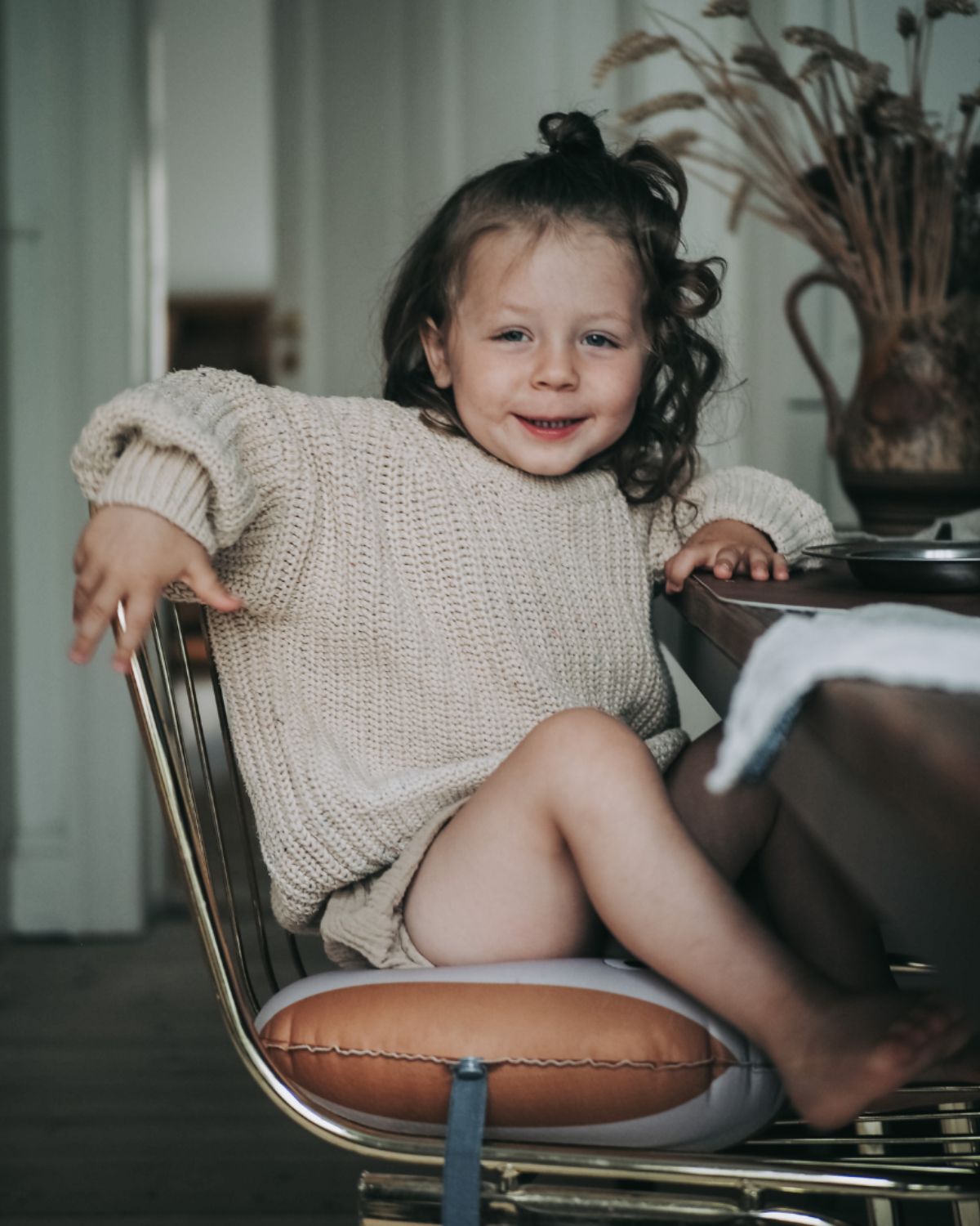 alt="Inflatable ergonomic booster cushion for children with elastic strap and anti-slip backing, placed on a dining chair"