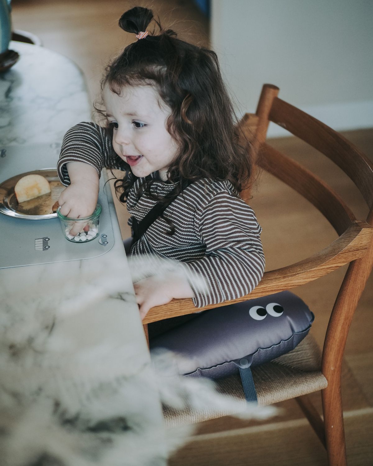 Inflatable ergonomic seat cushion in anthracite for children. Elastic strap to secure the seat cushion on a chair.