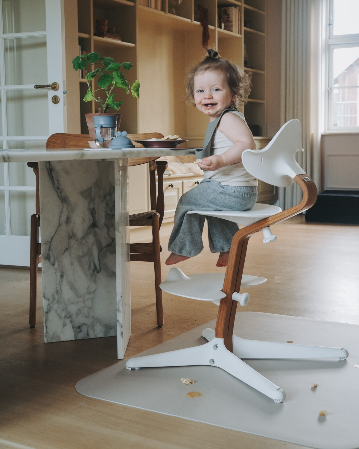 A high chair floor mat made of soft vinyl, in the color nude. A rectangular mat to protect all kind of floors from spills. Put it under the high chair.