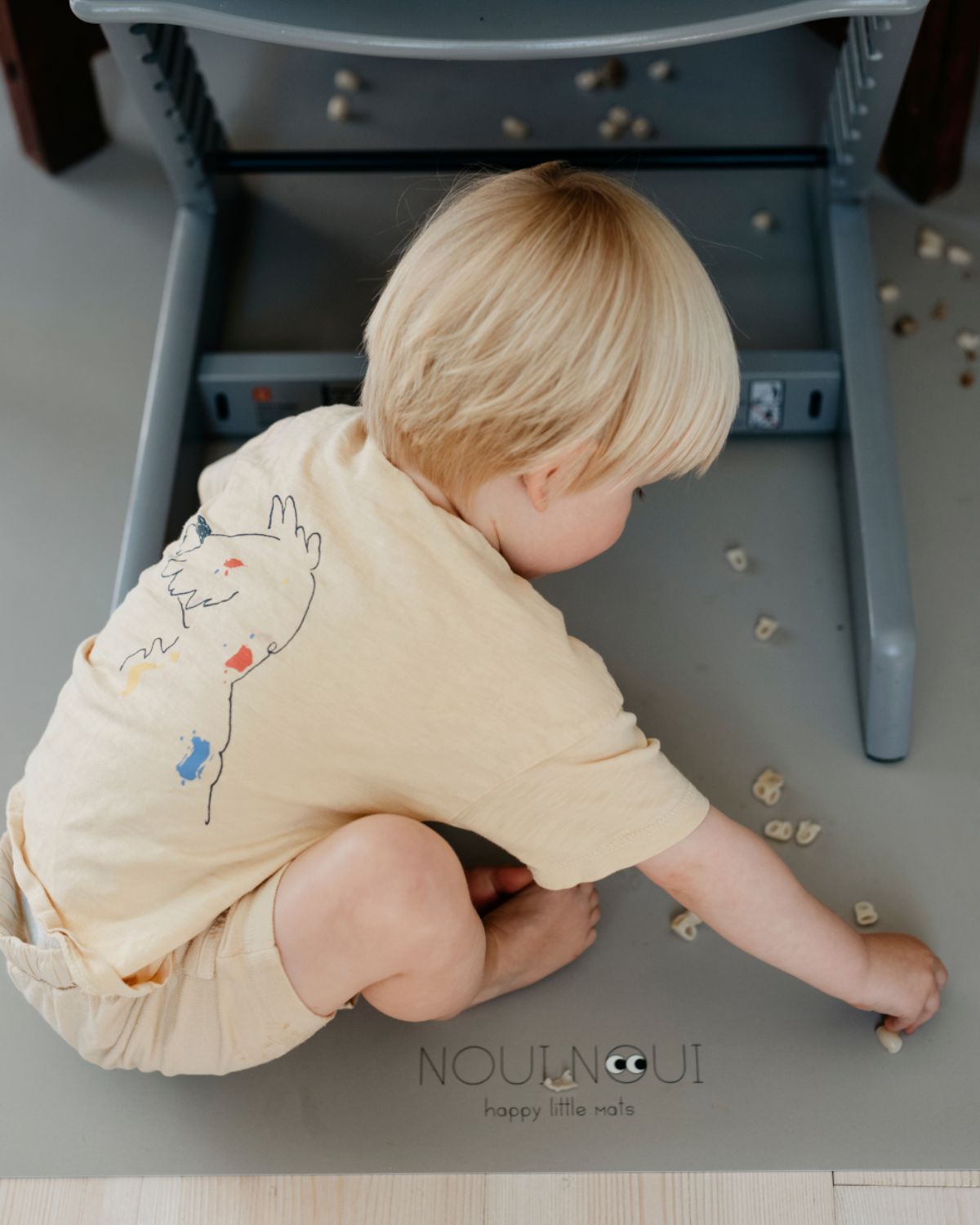 A high chair floor mat made of soft vinyl, in the color olive haze gray. A rectangular mat to protect all kind of floors from spills. Put it under the high chair. Easy to clean.