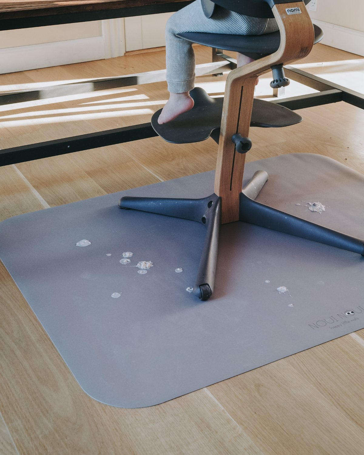 A high chair floor mat made of soft vinyl, in the color cocoa. A rectangular mat to protect all kind of floors from spills. Put it under the high chair.