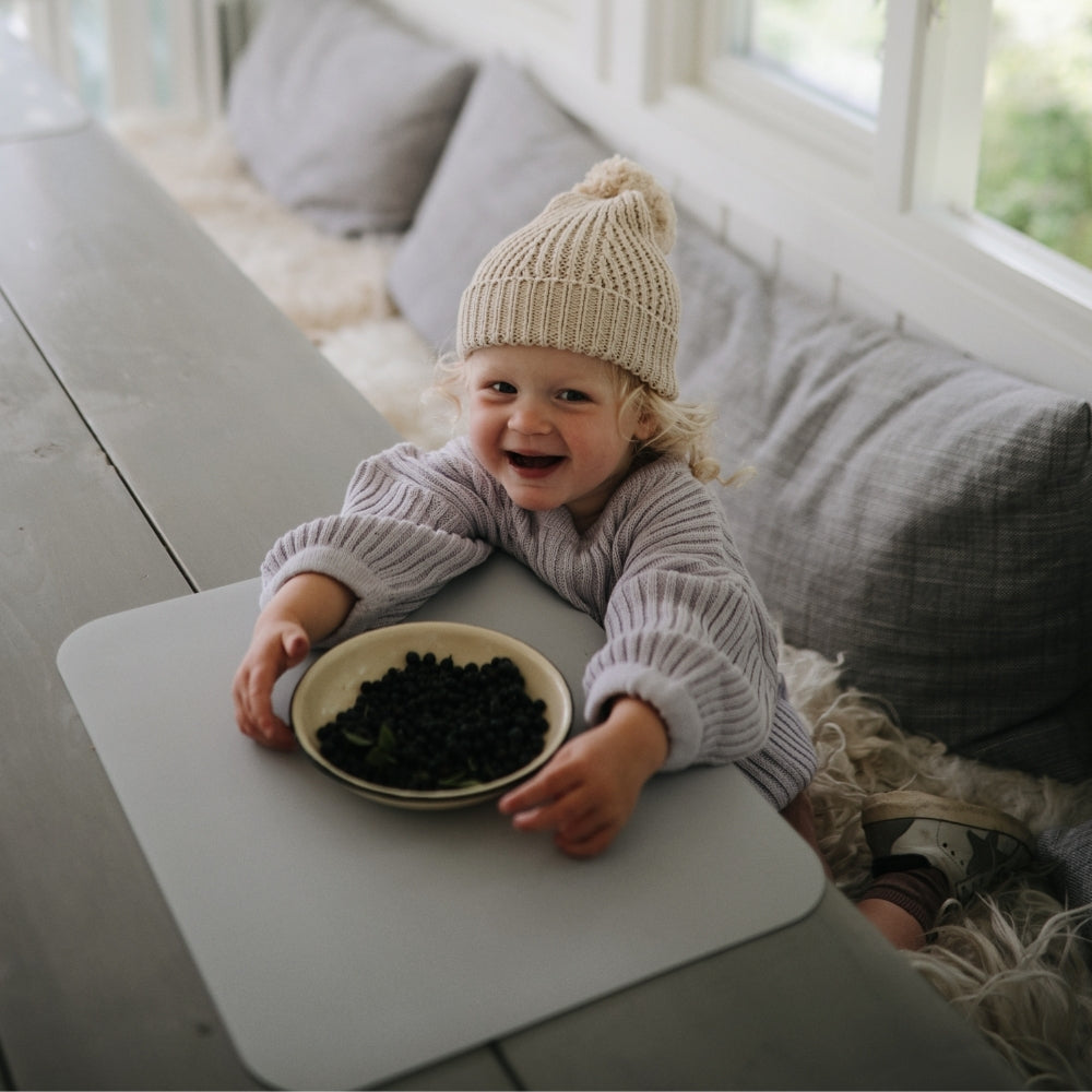 A child eating berries on our grey powder color placemat. Perfect to protect the table surface from spills and scratches.