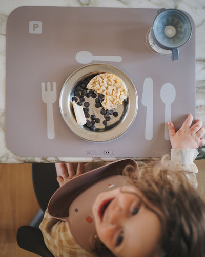 A cocoa brown learning placemat with illustrations of a plate, fork, knife, and spoon on it. Perfect helper when the child wants to help setting the table.