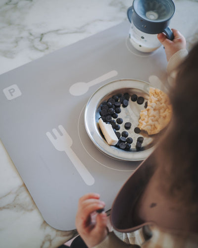 A grey powder learning placemat with illustrations of a plate, fork, knife, and spoon on it. Perfect helper when the child wants to help setting the table.