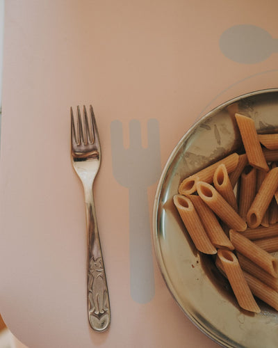 A nude learning placemat with illustrations of a plate, fork, knife, and spoon on it. Perfect helper when the child wants to help setting the table.
