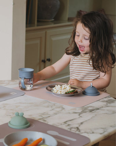 A nude learning placemat with illustrations of a plate, fork, knife, and spoon on it. Paired with placemat in cocoa and nude. 