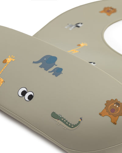 A close up of our soft silicone bib in olive haze gray color with various small animal illustrations and an adjustable neck strap.