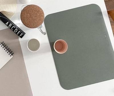 Placemat in dusty olive color. Displayed on a table with a glas.