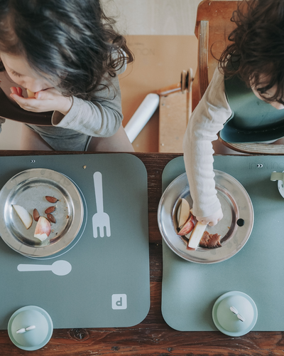 Child sitting at a table with Placemat in dusty olive color lying on a table.