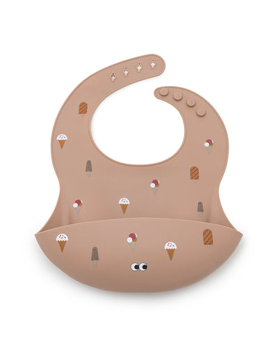 A silicone bib in dusty rose color with a pattern of different cute ice cream. The bib has an adjustable strap and an extra large cup to catch food and fluids. 