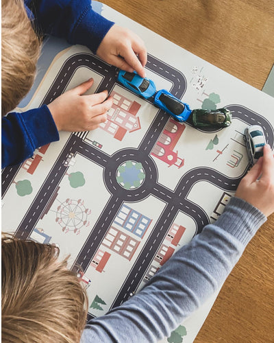 An XL placemat with different small cars and road map design, featuring buildings, trees, and a Ferris wheel.