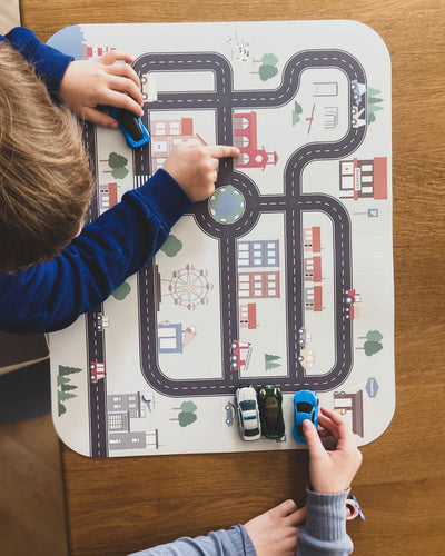 An XL placemat with different small cars and road map design, featuring buildings, trees, and a Ferris wheel.