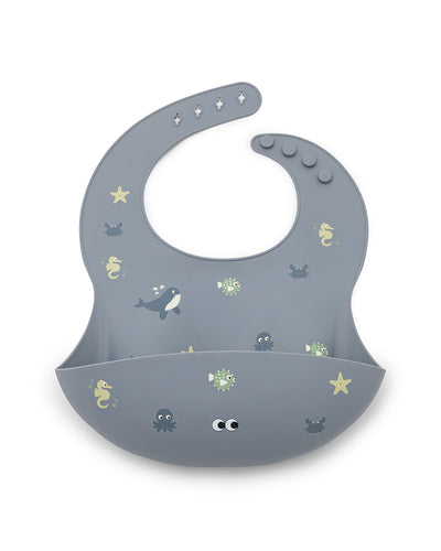 A soft silicone bib in dusty blue color with small see animal illustrations and an adjustable neck strap.