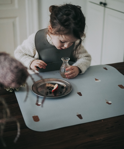 A child eating on our grey placemat with a pattern of various ice cream designs across the surface.