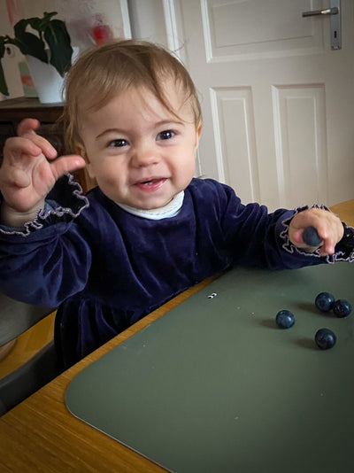 A child eating blueberries on our Placemat in dusty olive color. 