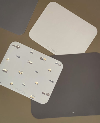 various placemats on a table among others Placemat in grey powder color with a pattern of cars and other vehicles in grey tones.