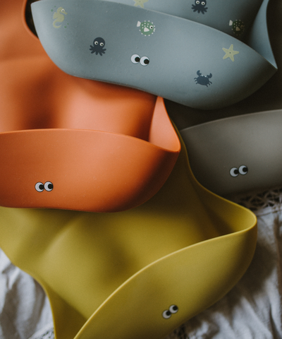 A selection of silicone bib in dusty lemon, dusty rusty, wild ocean and warm gray 